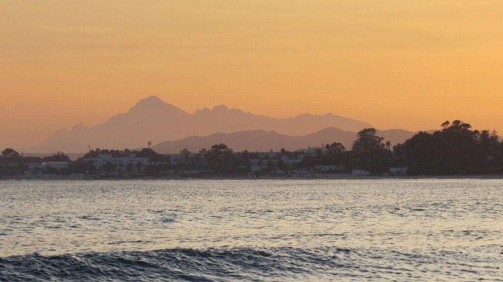 Profilo costiero di Hammamet visto dall'acqua: le caratteristiche case bianche della città vecchia protette dai bastioni della Kasbah lungo il Mediterraneo.